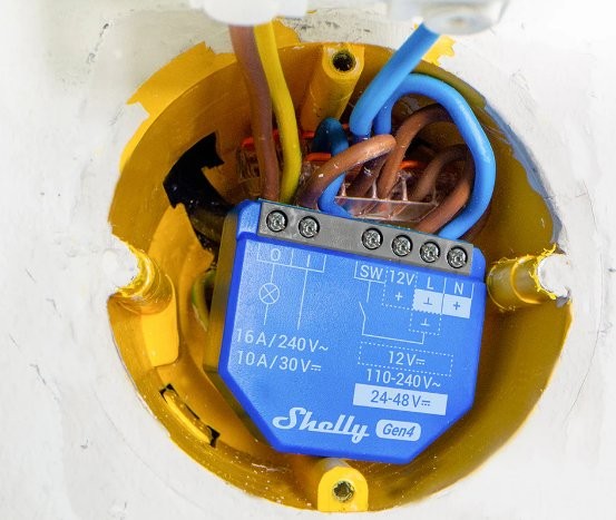 Shelly 1 Gen4 SW 12V – błękitny przełącznik elektryczny Zigbee/Matter w ścianie, podłączony do kabli.