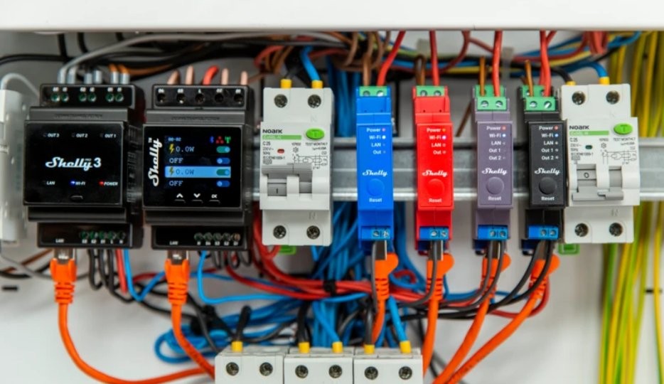Zestaw urządzeń IoT Shelly, w tym Shelly Pro 3 z ekranem LCD i cztery kolorowe przekaźniki