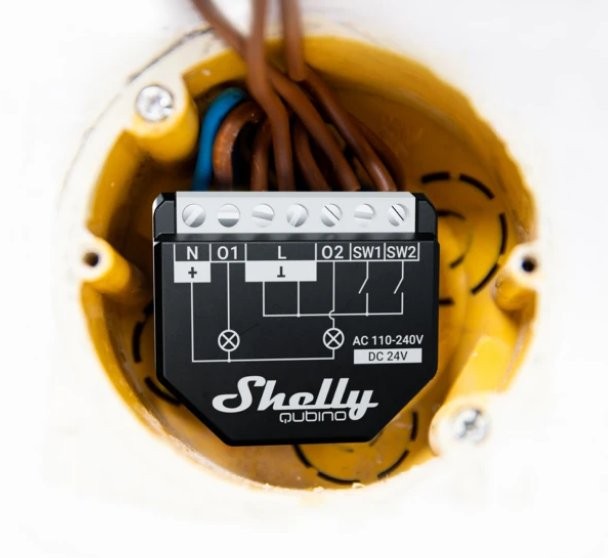 Moduł elektroniczny Shelly 1 zamontowany w ścianie, podłączony do przewodów elektrycznych