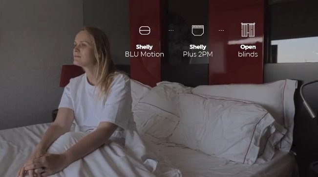 Kobieta siedząca na łóżku w pokoju kontrolując urządzenia IoT Shelly BLU Motion oraz inne produkty