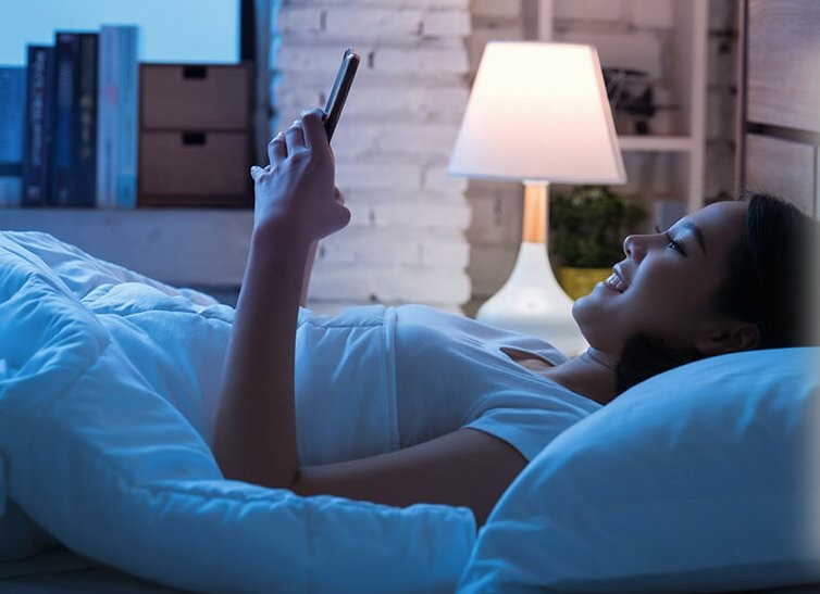 Nocne rozrywki Kobieta oglądająca coś na telefonie w nocy, przy świetle ekranu