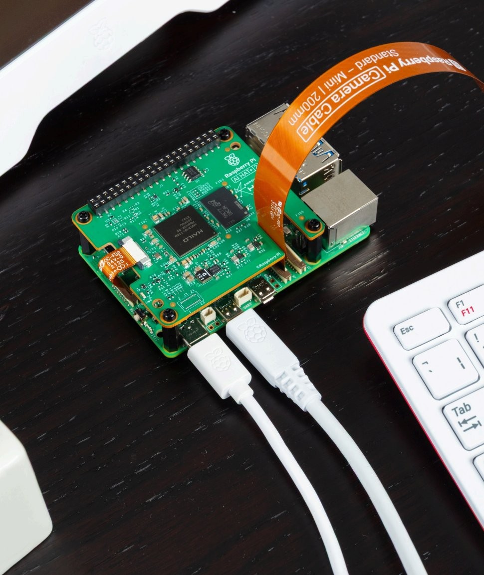 Raspberry Pi AI HAT+ 2 na Raspberry Pi 5 Raspberry Pi AI HAT+ 2 montowany na Raspberry Pi 5 z kablem kamerowym i USB, akcelerator AI dla lokalnego przetwarzania danych